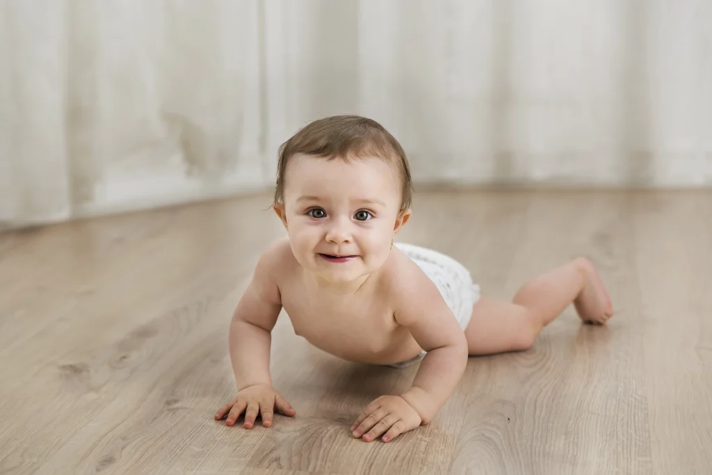 Kúszó kisbaba kamerába néz, kíváncsi tekintetű babafotózás műteremben