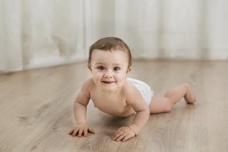 Kúszó kisbaba kamerába néz, kíváncsi tekintetű babafotózás műteremben