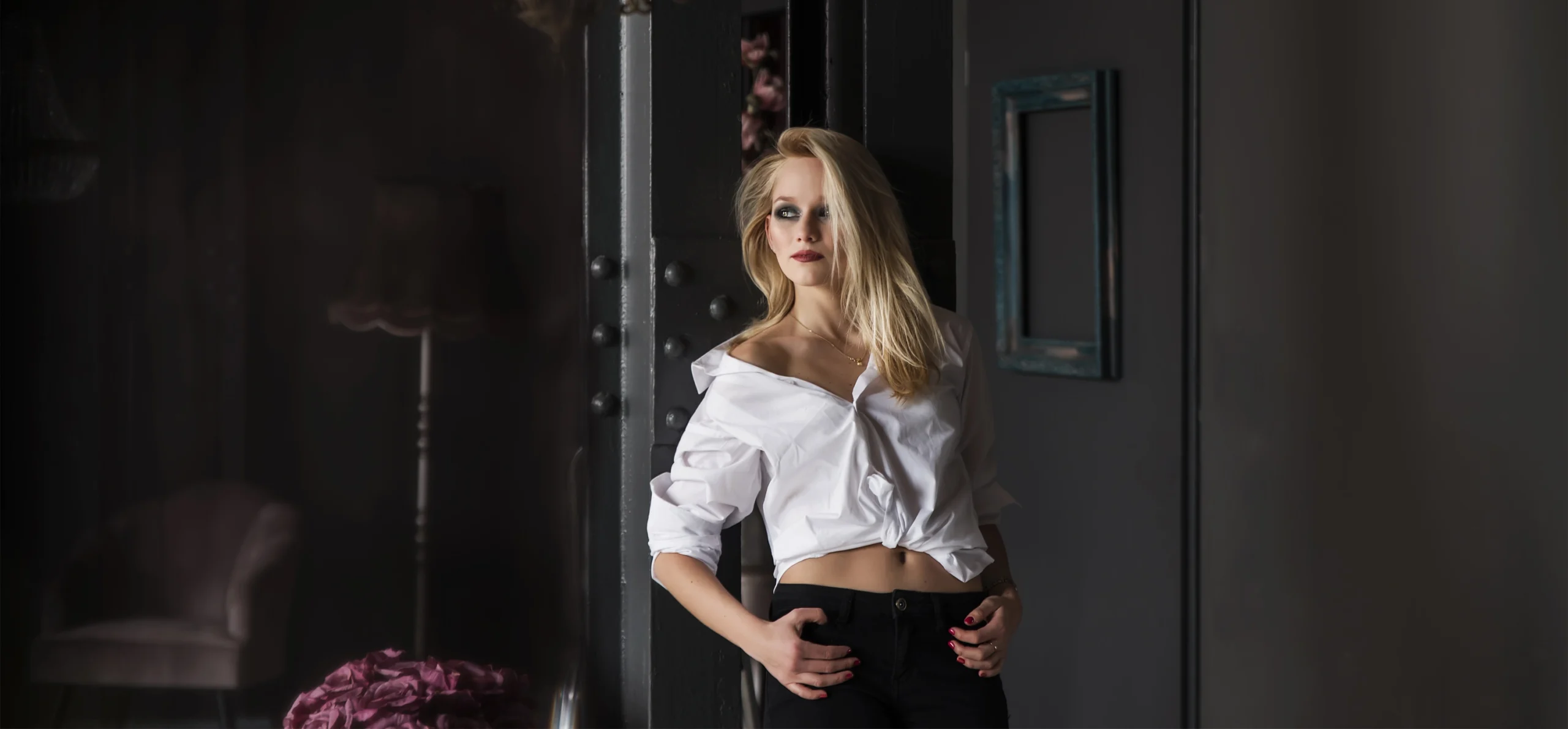 Elegáns hölgy kezét csípőjén tartva pózol glamour stílusú fotózáson