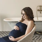 Székben ülő kismama várja gyermekét, meghitt terhesfotó természetes fényben