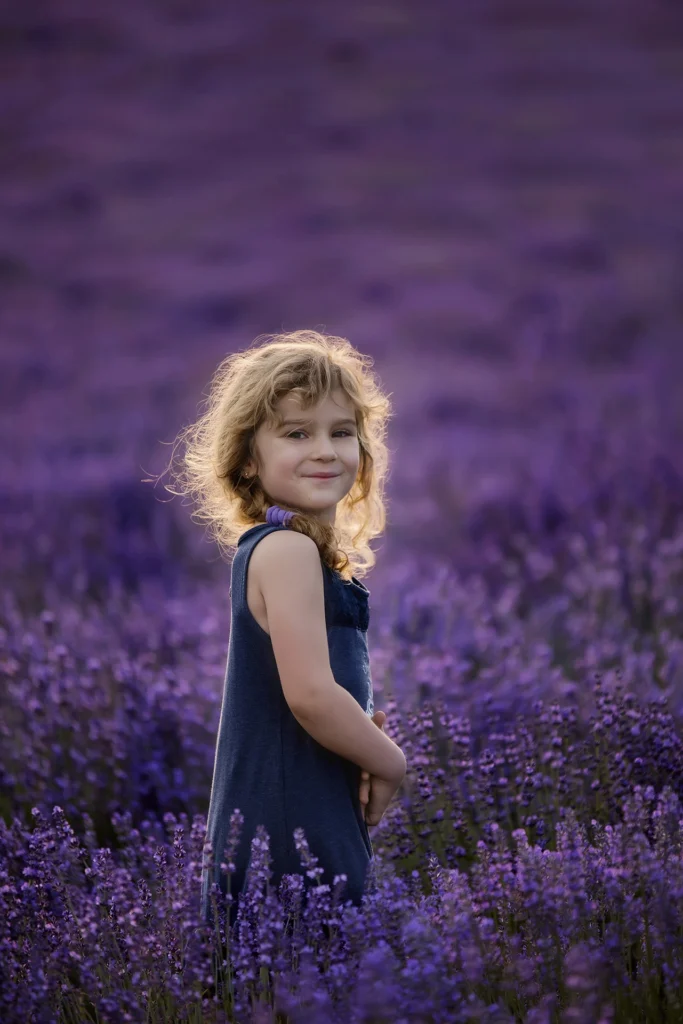 Mosolygós kislány lila levendulamezőn, szőke haja aranyként fénylik