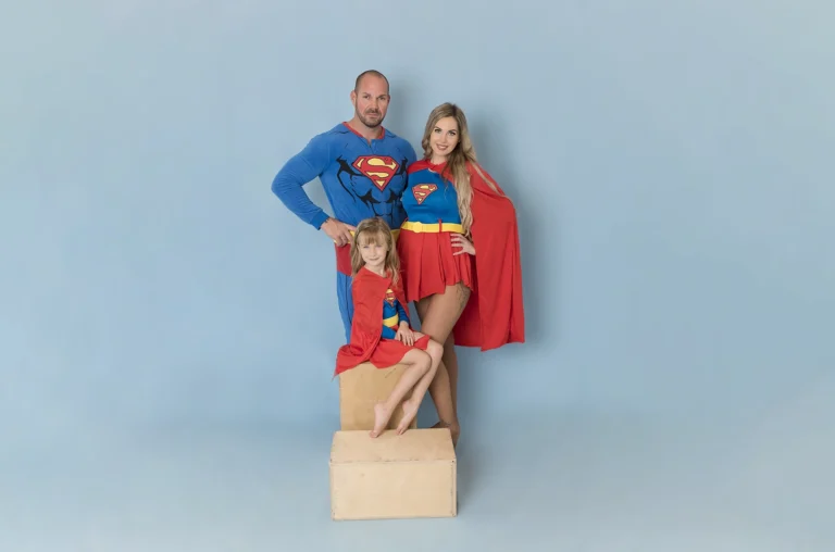 Suparman és Supergirl lányukkal kék hátteres fotózáson