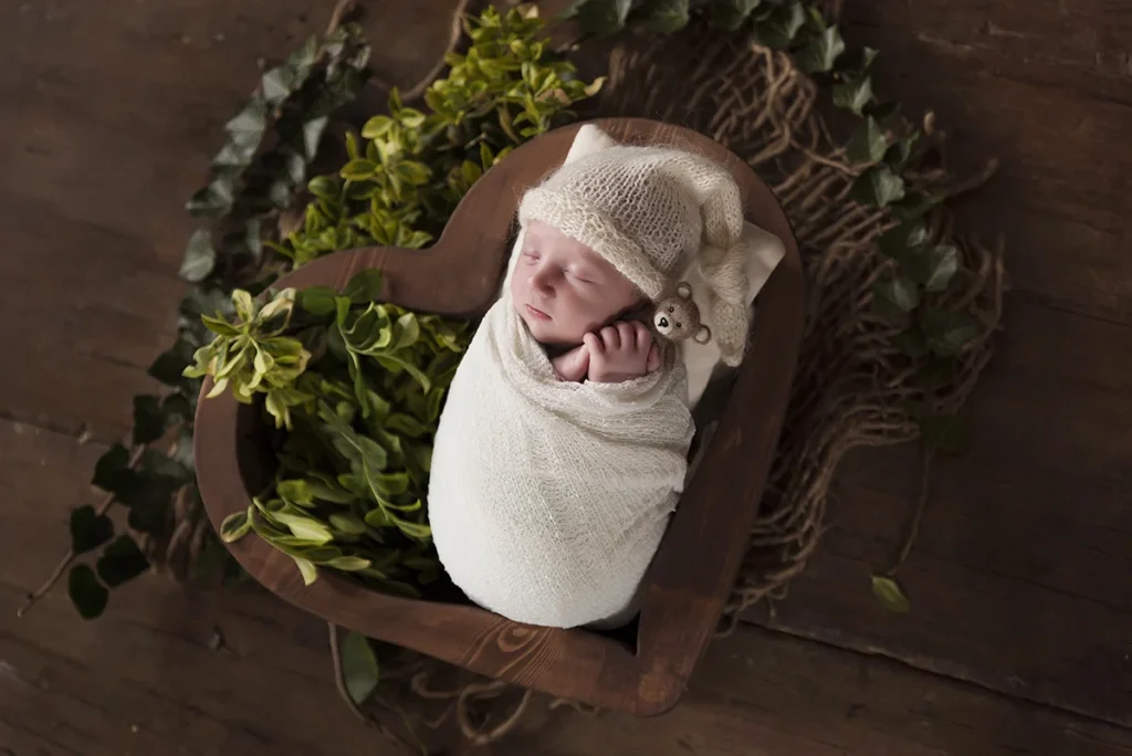 Kezdőlap Fehér wrapbe tekert alvó újszülött baba szív alakú dobozban, békés babaportré